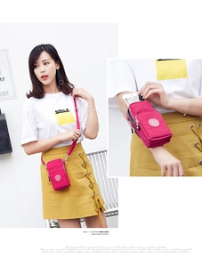 Detailed view of magenta nylon crossbody phone bag with multiple zipper compartments