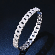 Macro view of silver Cuban link bracelet with half-pave crystals on dark background