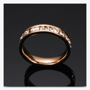Close-up of 4mm rose gold eternity ring with single row crystals on a black reflective surface