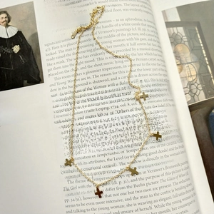 Detail of a gold multi-cross necklace laying on a vintage art book with aesthetic vibes