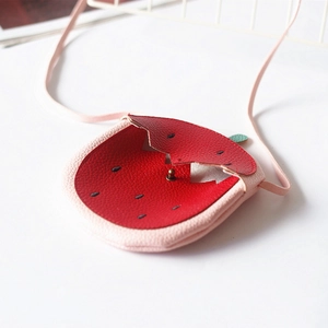 Detail showing pink strawberry crossbody bag with seed embroidery and green leaf accents