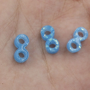 Macro view of blue infinity opal beads with glitter finish held in a palm for size