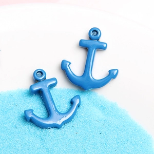 Blue anchor-shaped resin charms displayed on sand for DIY phone case craft decoration