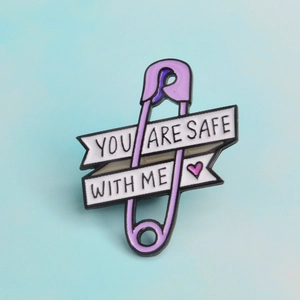 Macro detail of purple enamel safety pin brooch with You Are Safe With Me text and pink heart