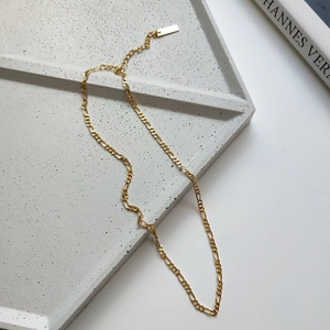 Golden Figaro chain necklace in 925 silver with adjustable extender on cement tray