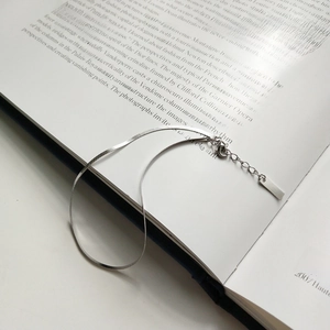 S925 sterling silver blade chain anklet placed elegantly on an open book page