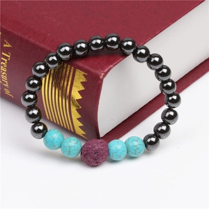 Close-up of black magnetic beads and turquoise bracelet resting on a red book cover