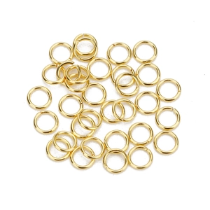 Macro shot of polished gold jump rings for DIY jewelry making on white background