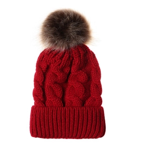 Gros plan détaillé d'un bonnet d'hiver en maille torsadée rouge avec pompon en fausse fourrure