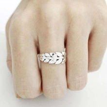 Close-up of silver feather ring with detailed metallic texture on person's hand