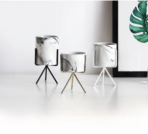 Detailed view of Nordic marble ceramic pots with minimalist gold and black tripod metal stands