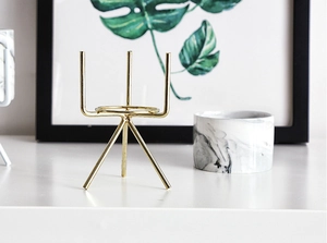 Detail of minimalist gold-coated iron plant stand with stable tripod structure