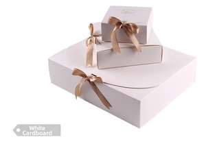 Three-piece nesting set of elegant ivory white gift boxes with champagne silk bows