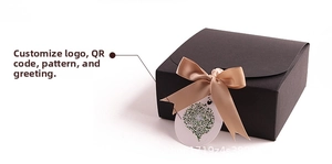 Detail of matte black flip-top gift box with champagne bow and custom hanging tag