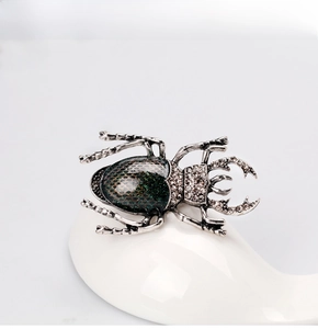 Detail of vintage beetle brooch with green enamel and sparkling white crystals