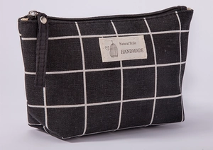 Gedetailleerd overzicht van de ruitjes canvas cosmetische tas met ritssluiting en label.