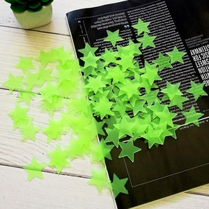 Macro shot of 3cm 3D glow-in-the-dark fluorescent green star wall stickers on a wood table