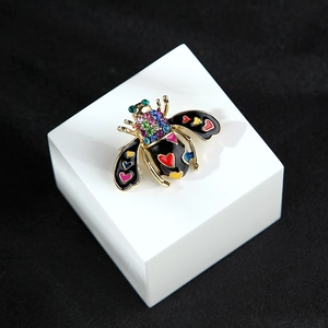 Detail of bee brooch with colorful rhinestone head and enamel wings with heart patterns