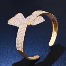 Detail of gold-plated cuff bangle featuring a hollow bow-knot design paved with zircons