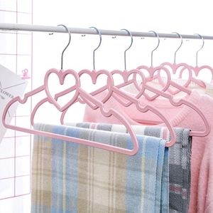 Pink heart-shaped non-slip plastic hanger with metal hook and hollow design on a rail