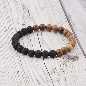 Detail of natural wood and black lava stone beads on a rustic wooden surface