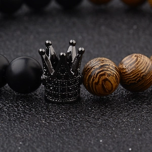 Macro shot of black crown charm with micro-pave stones on wooden beaded bracelet