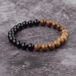 Close-up of polished black stones and natural grain wood beads on a minimalist bracelet
