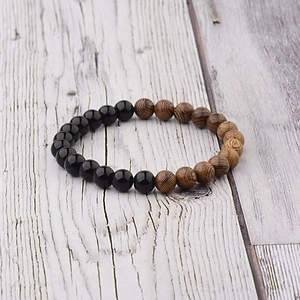 Detail of beaded bracelet featuring black onyx and striped wood beads on grey background