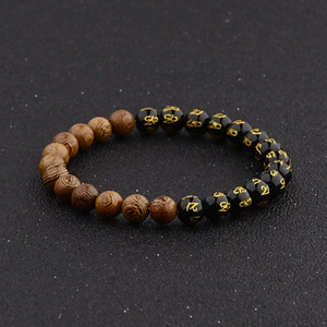 Macro detail of wooden beads and black beads with gold mantra characters on bracelet