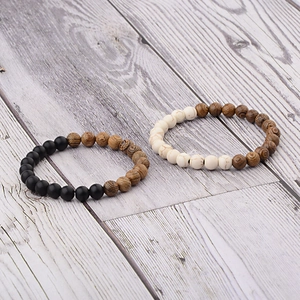 Detail of beaded bracelet set featuring black matte beads, white marble, and wood textures