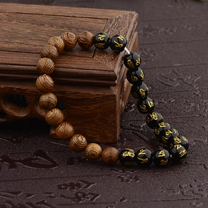 Macro detail of wooden prayer beads with golden Buddhist mantra engraving on black accent bead
