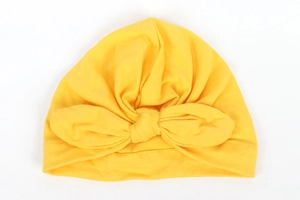 Detailed view of bright yellow baby turban hat with a large bow in soft knit fabric