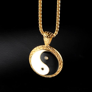 Macro shot of gold Tai Chi pendant with box chain featuring engraved edges and small crystals