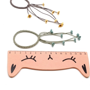 Sweet woven flower hair ties with streamers in brown and grey-green, size shown on ruler