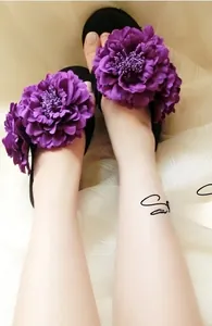 Close-up of black flip-flops featuring large purple silk peony flowers for summer