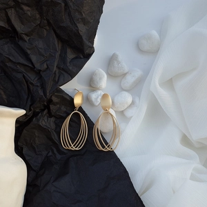 Minimalist matte gold geometric oval drop earrings on elegant artistic background