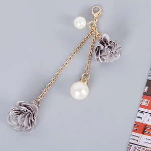 Detailed view of grey fabric flowers with white pearls and gold chain phone charm