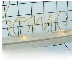 Nahaufnahme der goldenen LED-Nachtlampe in HOME-Form auf einem Holzsockel für Deko