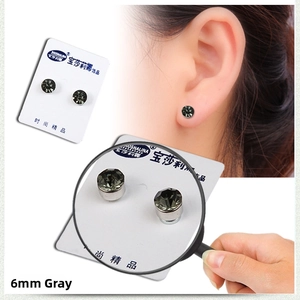 Macro detail of 6mm grey crystal magnetic stud earring with 4-claw setting on white background