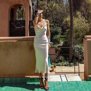 Robe longue élégante en satin blanc à fines bretelles sur un balcon exotique