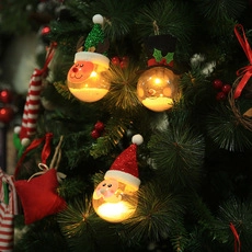 Detail of warm glowing Christmas bulb ornaments with festive plush figures on a tree