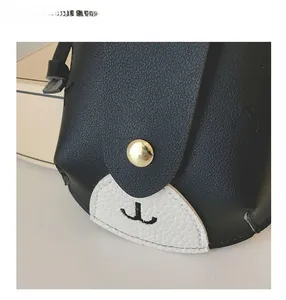 Close-up of cute cartoon small crossbody bag with gold snap button and lychee texture