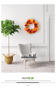 Autumn wreath with maple leaves and pumpkins hanging on a white wall above a sofa