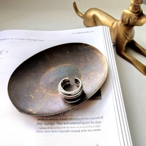 Macro shot of silver layered open ring on vintage book and bronze tray decor