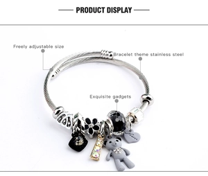 Detail of adjustable stainless steel charm bracelet with bear and flower pendants