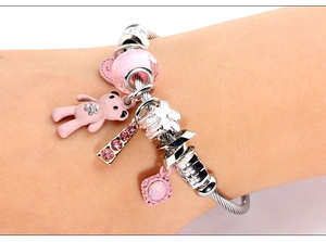 Detail of silver snake chain bracelet with pink bear charm and faceted beads on wrist