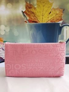Detail of pink makeup bag with embossed SOIGNE letters and golden zipper close-up