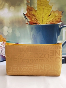 Close-up of yellow rectangular pouch with jacquard lettering in an autumn setting