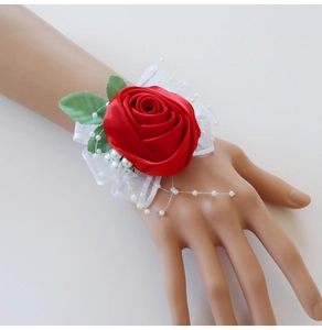 Detail of red satin rose wrist corsage with lace, white pearls, and green leaves