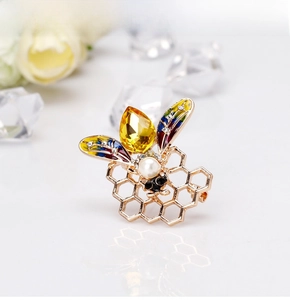 Macro shot of fashion bee brooch with golden enamel wings, pearls and yellow gemstone